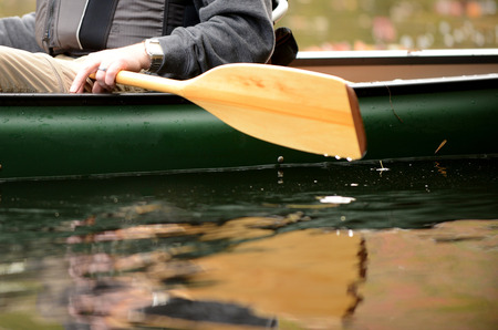 close-up image of a man on a river in a green canoe with a wooden paddleの写真素材