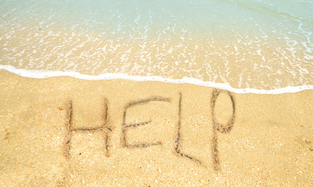 sos concept with help written in the sand on the shorelineの写真素材