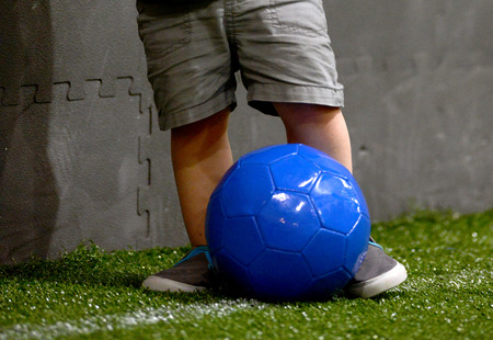 child with a blue soccer ball on artificial turn on a soccer fieldの写真素材