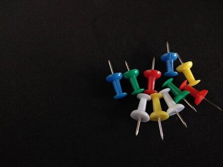 colorful push pins on black background