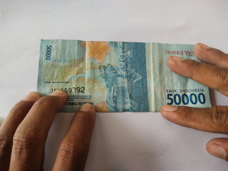 Asian man hand holding Indonesian banknotes.IDR banknotes,Indonesian money currency on white...