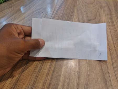Men hand holding blank paper on wooden table in the office, business concept