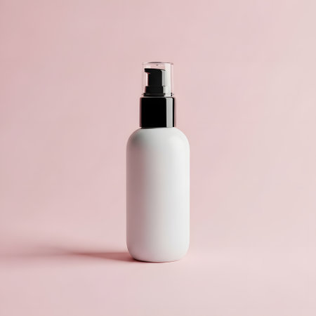 Blank white cosmetic bottle mockup on pastel pink background.の素材