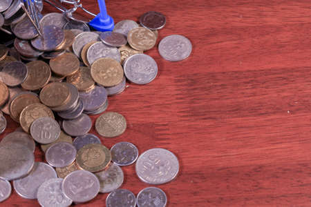 Miniature shopping cart full of coins on a wooden background- payments, investments and commerce conceptの写真素材