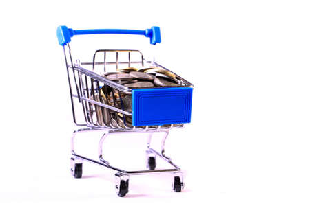 Miniature shopping cart full of coins on a wooden background- payments, investments and commerce conceptの写真素材