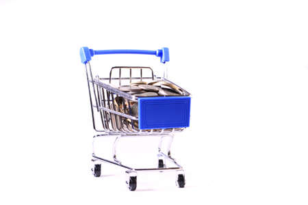 Miniature shopping cart full of coins on a wooden background- payments, investments and commerce conceptの写真素材