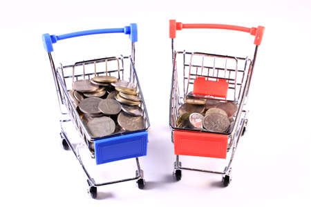 Miniature shopping cart full of coins on a wooden background- payments, investments and commerce conceptの写真素材