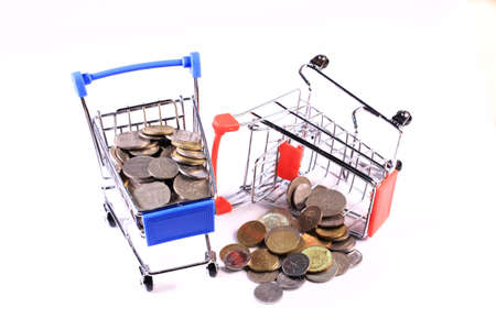 Miniature shopping cart full of coins on a wooden background- payments, investments and commerce conceptの写真素材