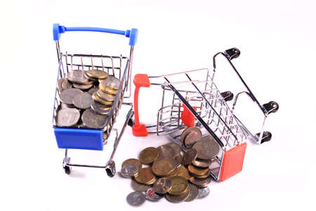 Miniature shopping cart full of coins on a wooden background- payments, investments and commerce conceptの写真素材