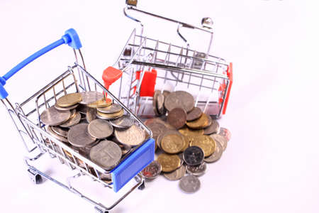 Miniature shopping cart full of coins on a wooden background- payments, investments and commerce conceptの写真素材