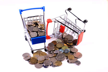 Miniature shopping cart full of coins on a wooden background- payments, investments and commerce conceptの写真素材