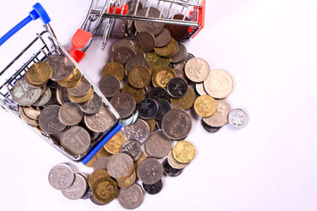 Miniature shopping cart full of coins on a wooden background- payments, investments and commerce conceptの写真素材