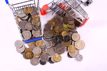 Miniature shopping cart full of coins on a wooden background- payments, investments and commerce conceptの写真素材