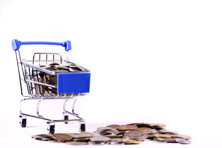 Miniature shopping cart full of coins on a wooden background- payments, investments and commerce conceptの写真素材