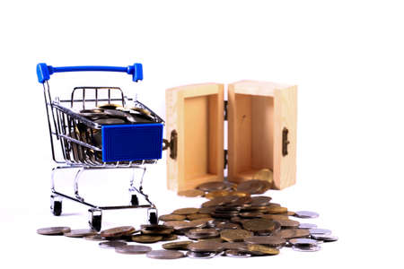 Miniature shopping cart full of coins on a wooden background- payments, investments and commerce conceptの写真素材
