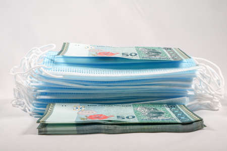 Face masks, the new world currency in Malaysia. Corona Cov19 crisis makes face mask to the most wanted equipment. Prices rising up. Mouth mask with Malaysia Ringgit money on a white background.の写真素材