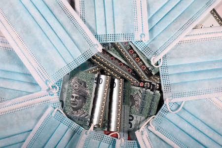 Face masks, the new world currency in Malaysia. Corona Cov19 crisis makes face mask to the most wanted equipment. Prices rising up. Mouth mask with Malaysia Ringgit money on a white background.の写真素材