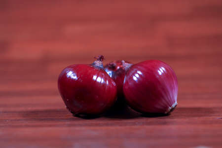 Red onions isolated on wooden background. Red onions are cultivars of the onion with purplish-red...