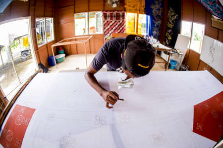 Kedah, MALAYSIA - Aug 13 2020 : Unidentified local woman/ men sketching freehand with canting tools and hot wax to create a traditional Batik Canting at workshop.のeditorial素材