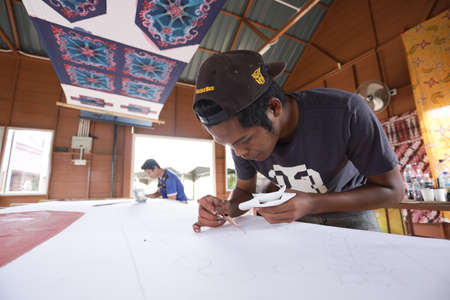 Kedah, MALAYSIA - Aug 13 2020 : Unidentified local woman/ men sketching freehand with canting tools and hot wax to create a traditional Batik Canting at workshop.のeditorial素材
