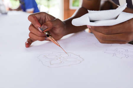 Unidentified local woman/ men sketching freehand with canting tools and hot wax to create a traditional Batik Canting at workshop.の写真素材