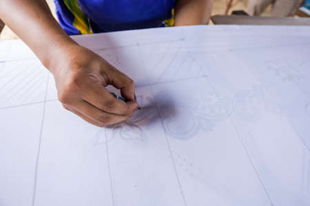 Unidentified local woman/ men sketching freehand with canting tools and hot wax to create a traditional Batik Canting at workshop.の写真素材