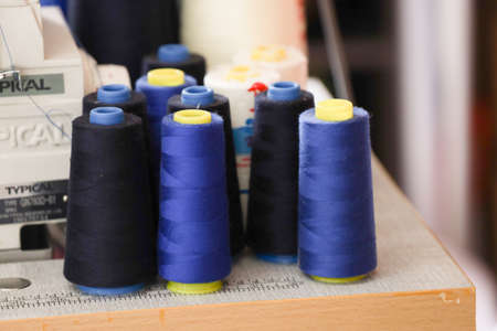 Colorful embroidery thread spool using in garment industry, row of multicolored yarn rolls, sewing...
