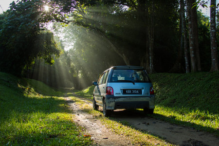Sintok, Kedah Malaysia - 12 Sept 2020 : Sun ray in forest with car, Ray of light in in green forest with carのeditorial素材