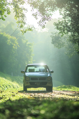 Sintok, Kedah Malaysia - 12 Sept 2020 : Sun ray in forest with car, Ray of light in in green forest with carのeditorial素材
