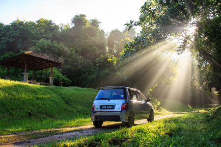 Sintok, Kedah Malaysia - 12 Sept 2020 : Sun ray in forest with car, Ray of light in in green forest with carのeditorial素材