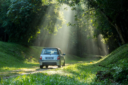 Sintok, Kedah Malaysia - 12 Sept 2020 : Sun ray in forest with car, Ray of light in in green forest with carのeditorial素材