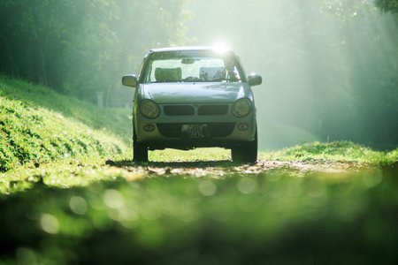 Sintok, Kedah Malaysia - 12 Sept 2020 : Sun ray in forest with car, Ray of light in in green forest with carのeditorial素材
