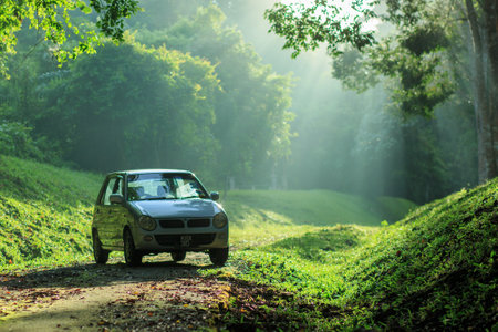 Sintok, Kedah Malaysia - 12 Sept 2020 : Sun ray in forest with car, Ray of light in in green forest with carのeditorial素材