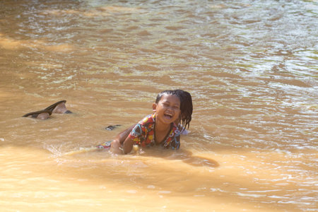 Changlun,Kedah Malaysia- Circa November 2020 : A group of kids playing on flood water 
in front of...