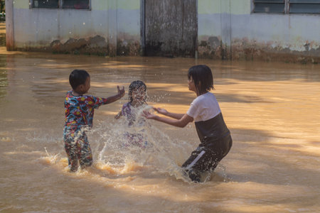 Changlun,Kedah Malaysia- Circa November 2020 : A group of kids playing on flood water 
in front of...