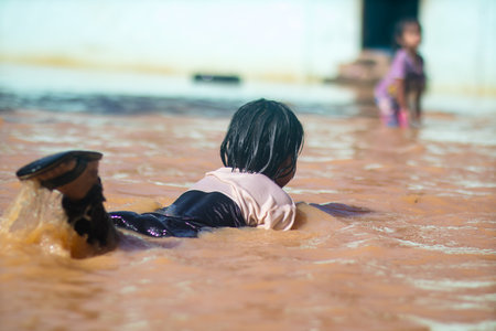 Changlun,Kedah Malaysia- Circa November 2020 : A group of kids playing on flood water 
in front of the houseのeditorial素材