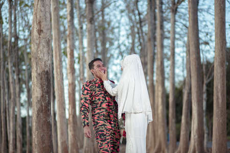 creative outdoor photo shoot of a malay loving couple bride and groom on their wedding wearing a traditional malay dress and camouflage dressの写真素材