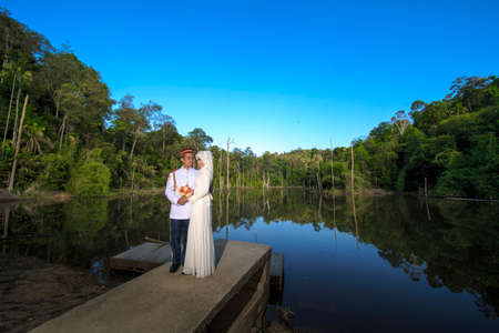 creative outdoor photo shoot of a malay loving couple bride and groom on their wedding wearing a traditional malay dress and camouflage dressの写真素材