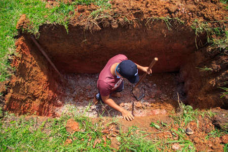Kedah, Malaysia -May 20, 2021: A man making a grave for funeral at Muslim cemetery.のeditorial素材
