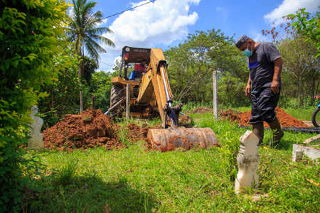 Kedah, Malaysia -May 20, 2021: A man making a grave for funeral at Muslim cemetery.のeditorial素材