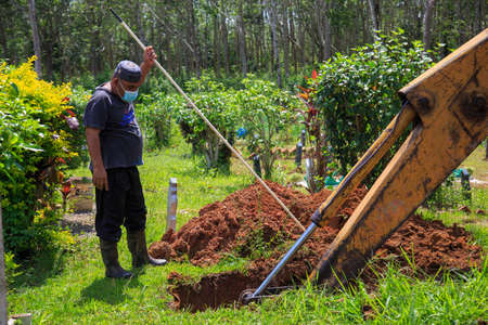 Kedah, Malaysia -May 20, 2021: A man making a grave for funeral at Muslim cemetery.のeditorial素材