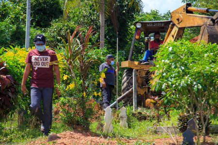 Kedah, Malaysia -May 20, 2021: A man making a grave for funeral at Muslim cemetery.のeditorial素材