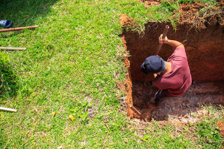 Kedah, Malaysia -May 20, 2021: A man making a grave for funeral at Muslim cemetery.のeditorial素材