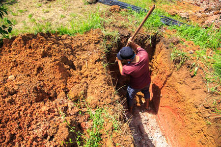 Kedah, Malaysia -May 20, 2021: A man making a grave for funeral at Muslim cemetery.のeditorial素材