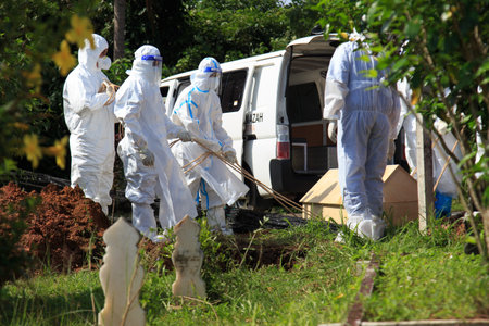 Kuala Lumpur, Malaysia may 2020 - Health workers wearing a PPE suit at graveyard during a funeral for Covid-19 victim in Kuala Lumpur.のeditorial素材