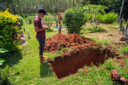 Kedah, Malaysia -May 20, 2021: A man making a grave for funeral at Muslim cemetery.のeditorial素材