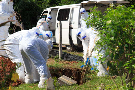 Kuala Lumpur, Malaysia may 2020 - Health workers wearing a PPE suit at graveyard during a funeral for Covid-19 victim in Kuala Lumpur.のeditorial素材