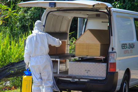 Kuala Lumpur, Malaysia may 2020 - Health workers wearing a PPE suit at graveyard during a funeral for Covid-19 victim in Kuala Lumpur.のeditorial素材