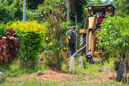 Kedah, Malaysia -May 20, 2021: A man making a grave for funeral at Muslim cemetery.のeditorial素材