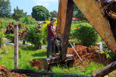 Kedah, Malaysia -May 20, 2021: A man making a grave for funeral at Muslim cemetery.のeditorial素材